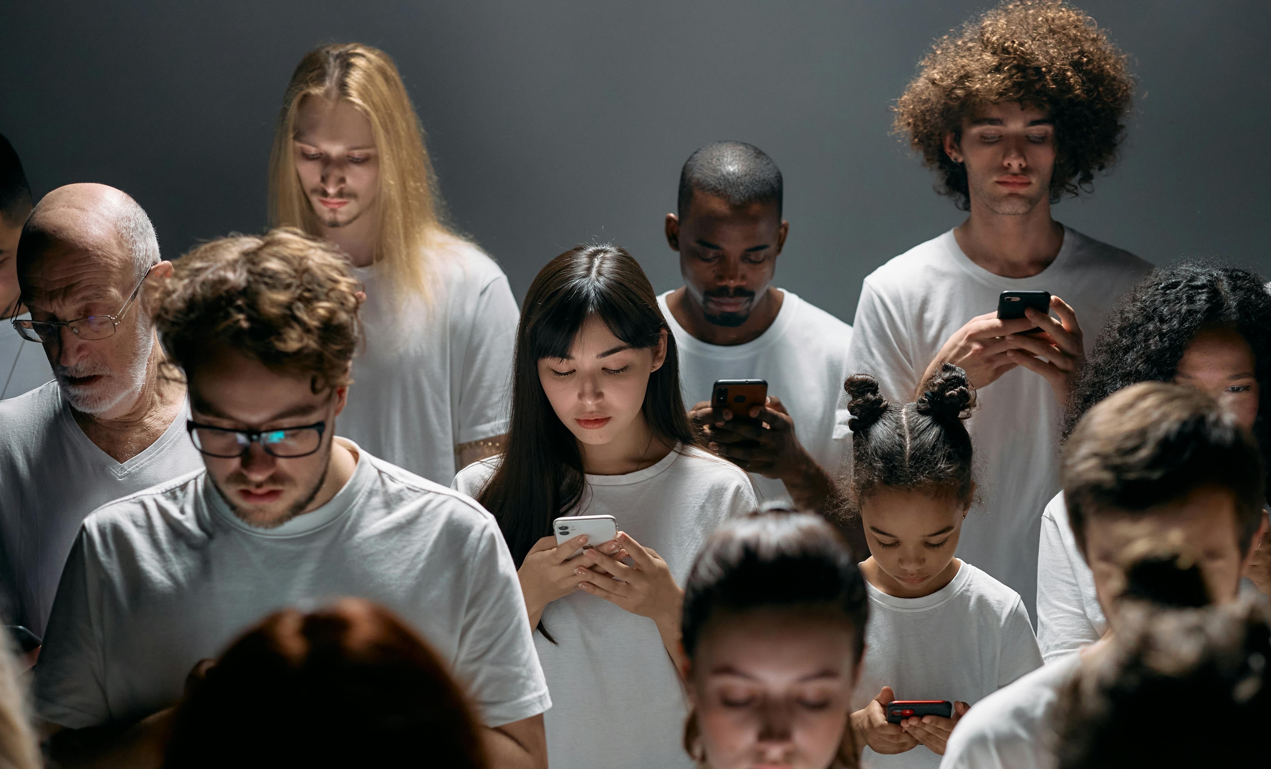 Verschillende mensen die hetzelfde gekleed zijn en op hun smartphone kijken, zonder aandacht voor elkaar