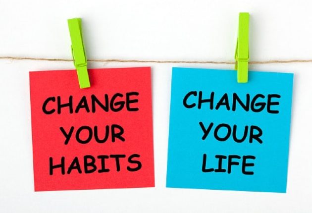 Change Your Life by Changing Your Habits text written on color notes with wooden pinch.